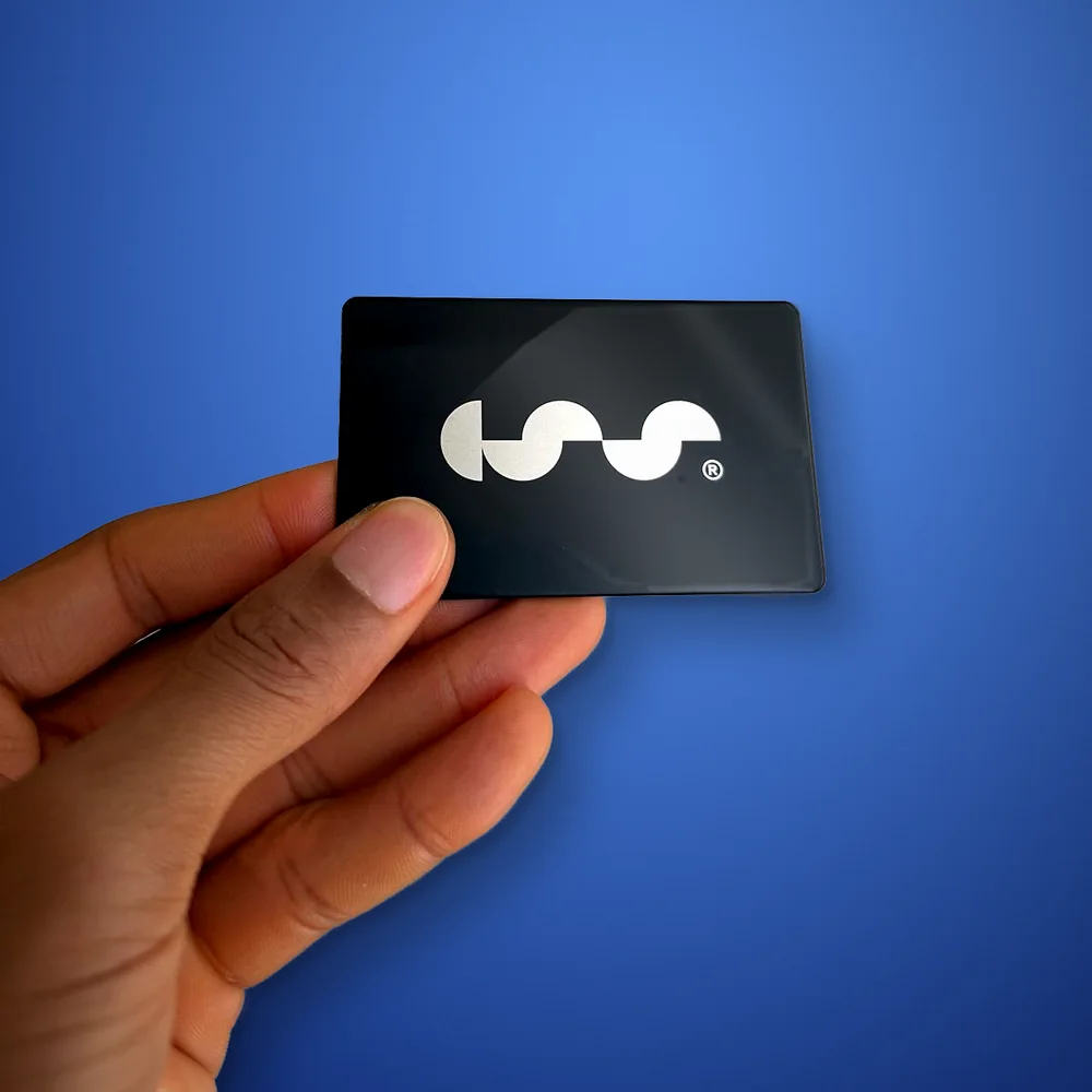 A hand holding a black metal business card with the silver CSS logo